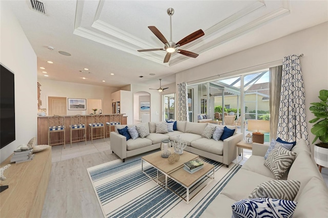 11915 Oak Ridge Dr, Parrish, FL 34219 - living room featuring a ceiling fan, a tray ceiling, light wood-style floors, ornamental molding, and arched walkways