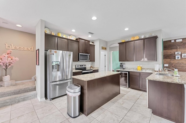 9123 Raes Creek Pl, Palmetto, FL 34221 - kitchen with stainless steel appliances, wine cooler, dark brown cabinets, light stone countertops, and a center island