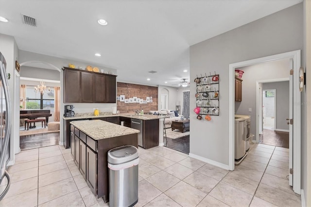 9123 Raes Creek Pl, Palmetto, FL 34221 - kitchen featuring washing machine and clothes dryer, dark brown cabinets, recessed lighting, a center island, and light tile patterned floors