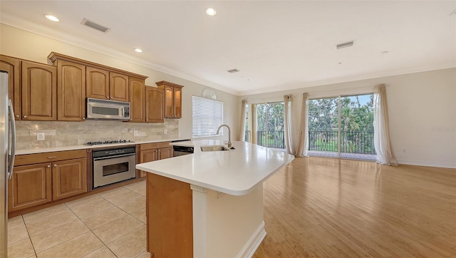 1512 3rd Street Cir E, Palmetto, FL 34221 - kitchen with stainless steel appliances, brown cabinets, a center island with sink, light countertops, and ornamental molding