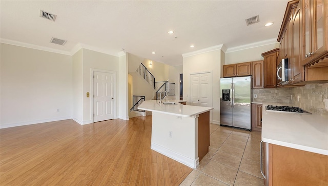 1512 3rd Street Cir E, Palmetto, FL 34221 - kitchen featuring appliances with stainless steel finishes, ornamental molding, light countertops, a kitchen island with sink, and backsplash