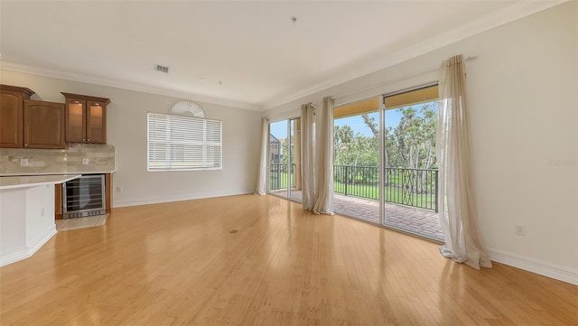 1512 3rd Street Cir E, Palmetto, FL 34221 - unfurnished living room with wine cooler, ornamental molding, and light wood-style flooring
