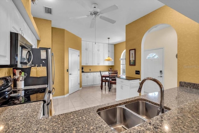 6908 Stoneywalk Ct, Bradenton, FL 34203 - kitchen featuring electric stove, stainless steel microwave, ceiling fan, white cabinetry, and arched walkways