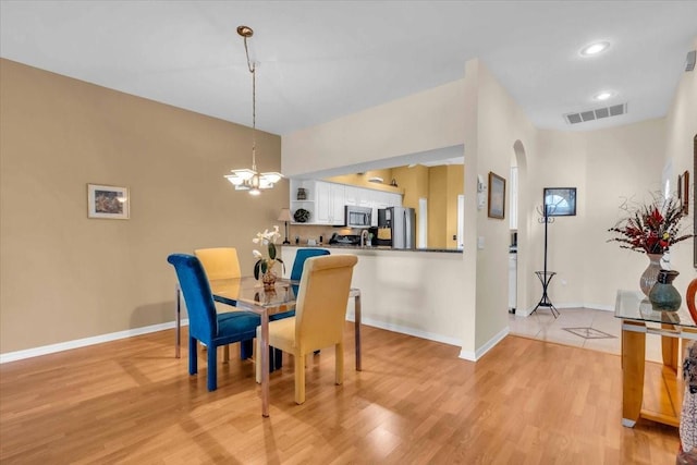 6908 Stoneywalk Ct, Bradenton, FL 34203 - dining area with arched walkways, light wood-style floors, and a chandelier