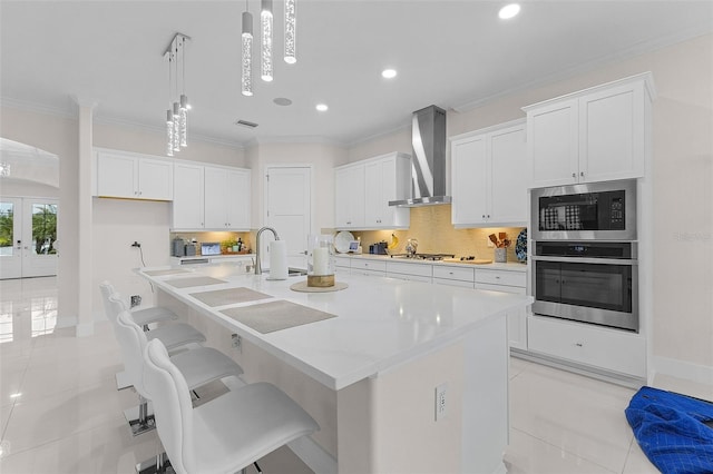 17204 Bullhorn Cir, Punta Gorda, FL 33982 - kitchen with stainless steel appliances, wall chimney range hood, light tile patterned flooring, white cabinetry, and ornamental molding