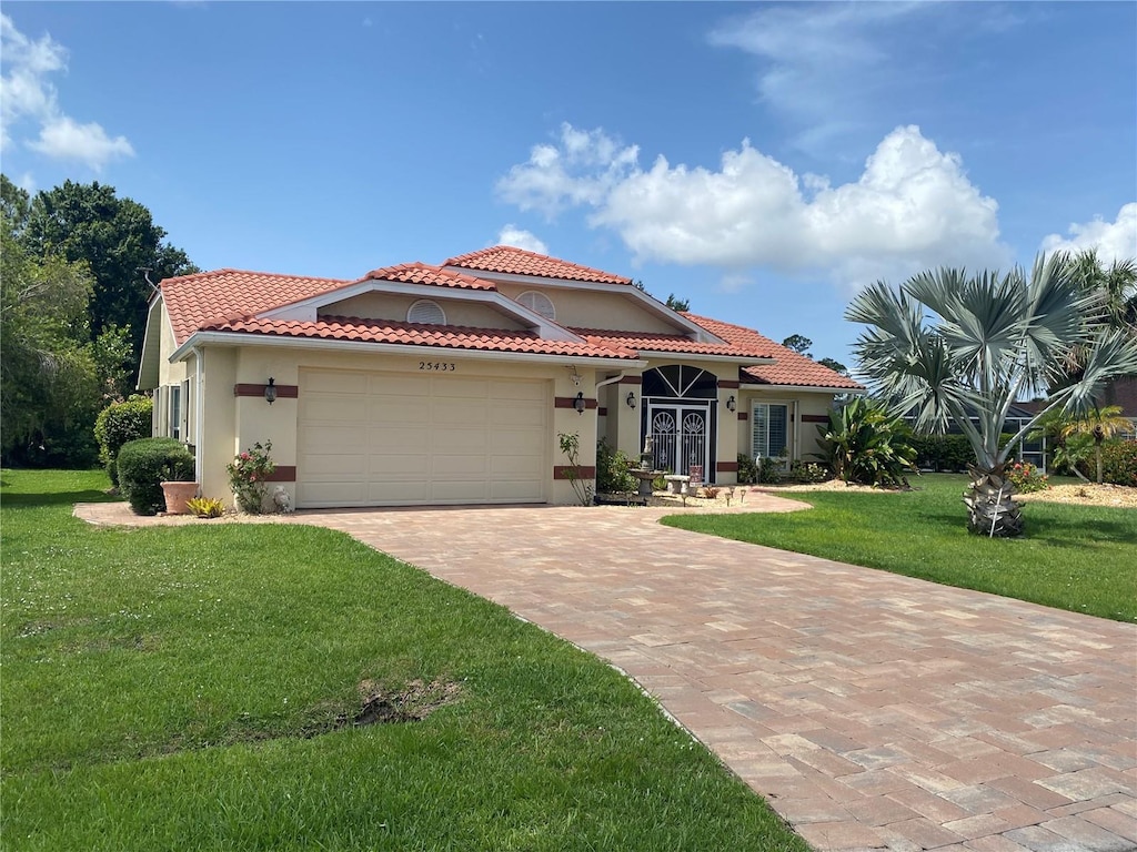 25433 Colon Dr, Punta Gorda, FL 33983 - mediterranean / spanish-style house featuring stucco siding, an attached garage, a front yard, and decorative driveway