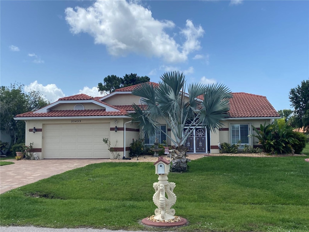 25433 Colon Dr, Punta Gorda, FL 33983 - mediterranean / spanish-style house with a front lawn, stucco siding, a garage, driveway, and a tiled roof