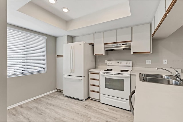 7866 Eagle Creek Dr Unit 7866, Sarasota, FL 34243 - kitchen with under cabinet range hood, white appliances, a tray ceiling, light wood-style flooring, and white cabinetry