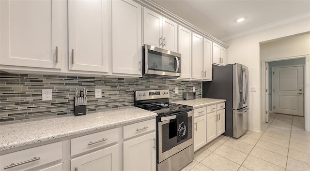 5910 Hevena Ct, Palmetto, FL 34221 - kitchen with appliances with stainless steel finishes, light tile patterned flooring, ornamental molding, tasteful backsplash, and white cabinets