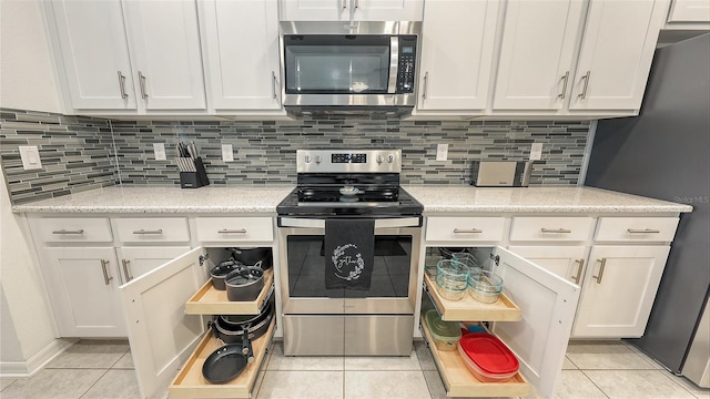 5910 Hevena Ct, Palmetto, FL 34221 - kitchen featuring appliances with stainless steel finishes, light tile patterned flooring, white cabinetry, and tasteful backsplash