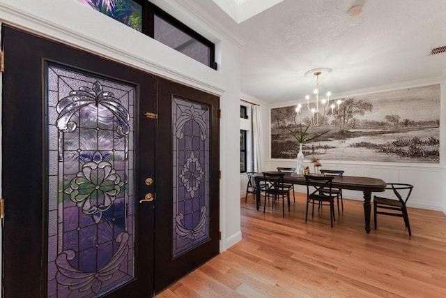 9122 16th Avenue Cir NW, Bradenton, FL 34209 - entrance foyer with a chandelier, ornamental molding, light wood-style floors, wainscoting, and a skylight