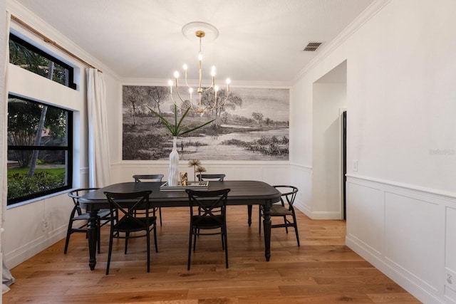 9122 16th Avenue Cir NW, Bradenton, FL 34209 - dining space with a chandelier, wainscoting, ornamental molding, wood finished floors, and a decorative wall