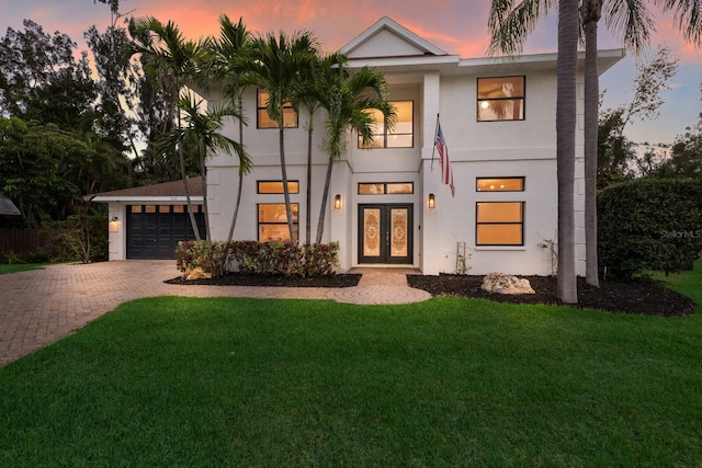 9122 16th Avenue Cir NW, Bradenton, FL 34209 - view of front of house featuring french doors, decorative driveway, a lawn, an attached garage, and stucco siding