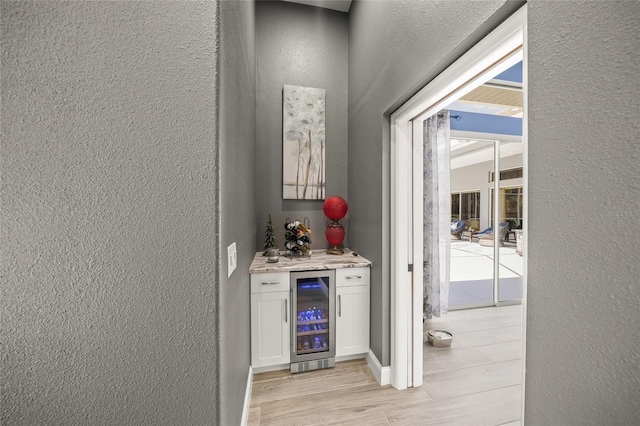8924 Misty Creek Dr, Sarasota, FL 34241 - indoor dry bar with beverage cooler, a textured wall, and light wood-type flooring
