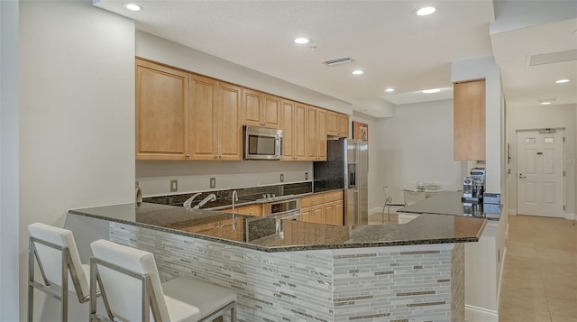 610 Riviera Dunes Way Unit 306, Palmetto, FL 34221 - kitchen featuring appliances with stainless steel finishes, dark stone counters, light tile patterned floors, a peninsula, and recessed lighting