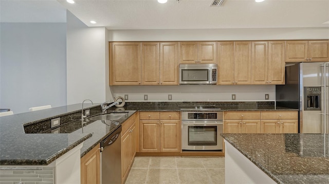 610 Riviera Dunes Way Unit 306, Palmetto, FL 34221 - kitchen featuring stainless steel appliances, dark stone counters, recessed lighting, a peninsula, and light tile patterned floors