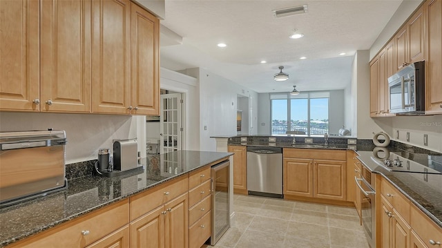 610 Riviera Dunes Way Unit 306, Palmetto, FL 34221 - kitchen featuring stainless steel appliances, beverage cooler, dark stone counters, a peninsula, and recessed lighting