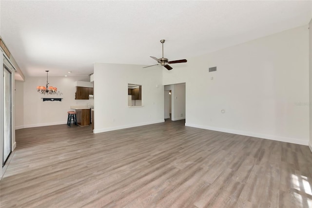 26147 L And J Rd, Myakka City, FL 34251 - unfurnished living room with light wood-style flooring, ceiling fan, and a chandelier