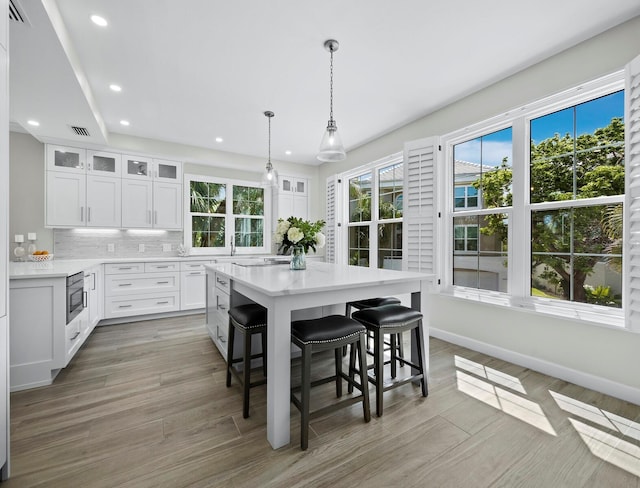 3959 Somerset Dr, Sarasota, FL 34242 - kitchen featuring a breakfast bar, recessed lighting, light countertops, white cabinetry, and glass insert cabinets