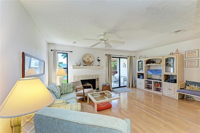 6840 Midnight Pass Rd Unit 6840, Sarasota, FL 34242 - living area featuring light wood-style floors, a textured ceiling, a ceiling fan, healthy amount of natural light, and a fireplace