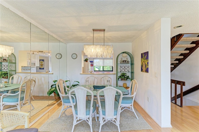 6840 Midnight Pass Rd Unit 6840, Sarasota, FL 34242 - dining room featuring a chandelier, wood finished floors, stairs, and a textured ceiling