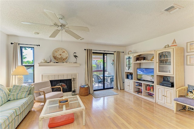 6840 Midnight Pass Rd Unit 6840, Sarasota, FL 34242 - living area with a textured ceiling, wood finished floors, plenty of natural light, a ceiling fan, and a fireplace