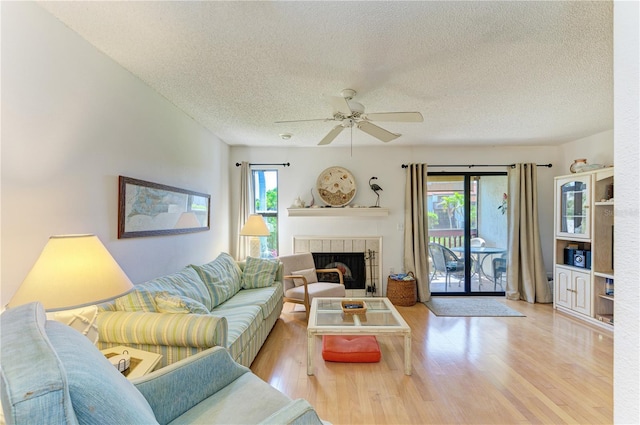 6840 Midnight Pass Rd Unit 6840, Sarasota, FL 34242 - living room with a textured ceiling, plenty of natural light, a ceiling fan, wood finished floors, and a tiled fireplace