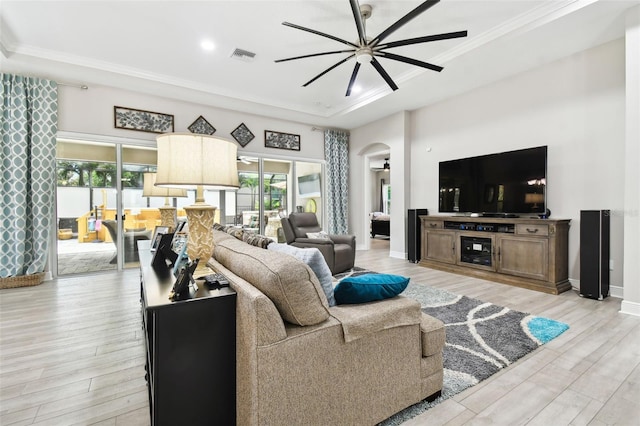 5802 Alabaster Stone Ln, Apollo Beach, FL 33572 - living area featuring a ceiling fan, a raised ceiling, arched walkways, light wood-style floors, and ornamental molding
