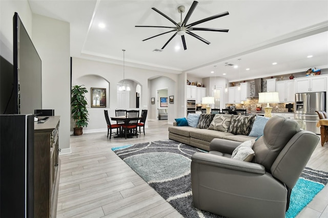 5802 Alabaster Stone Ln, Apollo Beach, FL 33572 - living area featuring arched walkways, light wood-style floors, a ceiling fan, recessed lighting, and a tray ceiling