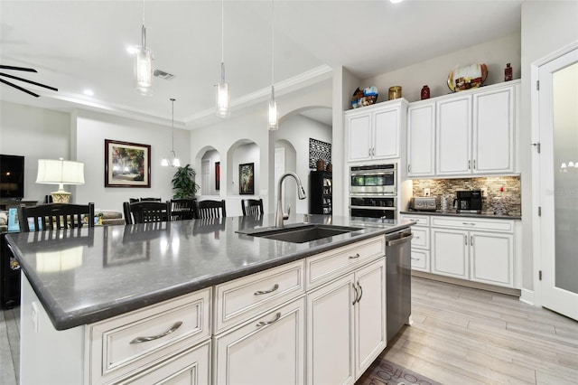 5802 Alabaster Stone Ln, Apollo Beach, FL 33572 - kitchen featuring arched walkways, stainless steel appliances, dark countertops, a large island, and light wood-type flooring