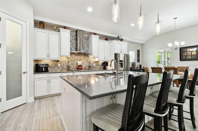 5802 Alabaster Stone Ln, Apollo Beach, FL 33572 - kitchen with wall chimney range hood, backsplash, dark countertops, stainless steel fridge with ice dispenser, and a kitchen island with sink