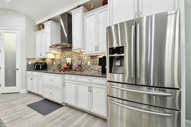 5802 Alabaster Stone Ln, Apollo Beach, FL 33572 - kitchen with stainless steel appliances, wall chimney range hood, dark countertops, light wood-style floors, and vaulted ceiling