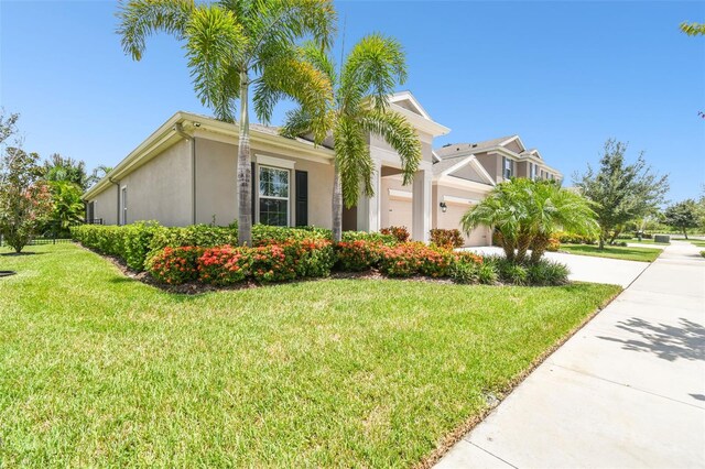 5802 Alabaster Stone Ln, Apollo Beach, FL 33572 - view of home's exterior featuring stucco siding, a lawn, an attached garage, and concrete driveway
