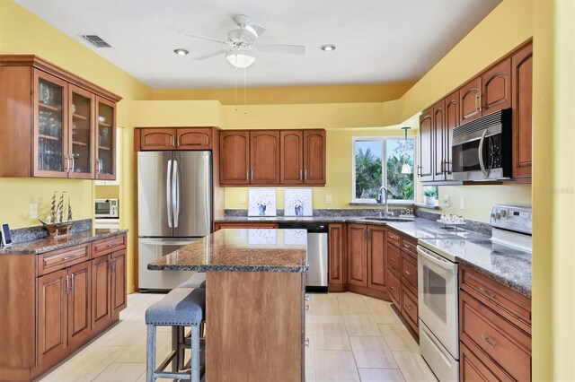175 Inlets Blvd Unit 175, Nokomis, FL 34275 - kitchen with appliances with stainless steel finishes, a center island, a kitchen breakfast bar, glass insert cabinets, and dark stone counters