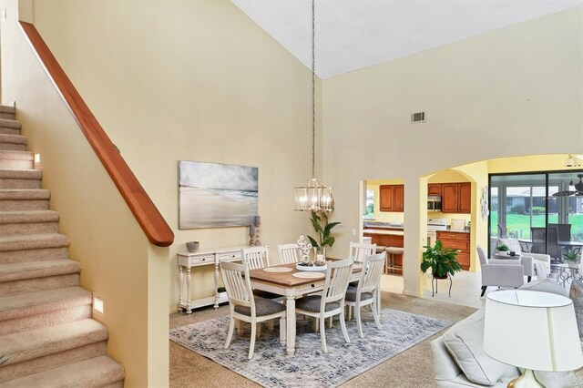 175 Inlets Blvd Unit 175, Nokomis, FL 34275 - dining room with high vaulted ceiling, light carpet, stairs, arched walkways, and a chandelier