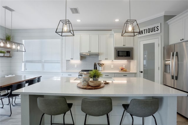 5419 Lakehurst Ct, Palmetto, FL 34221 - kitchen featuring stainless steel appliances, tasteful backsplash, white cabinetry, a kitchen bar, and a kitchen island with sink