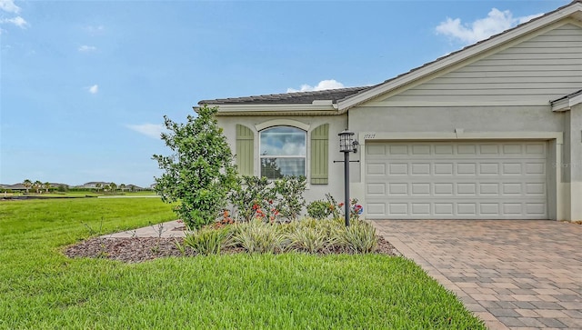 17817 Pastureland Ave, Lakewood Ranch, FL 34211 - view of side of home with a yard, stucco siding, decorative driveway, and a garage