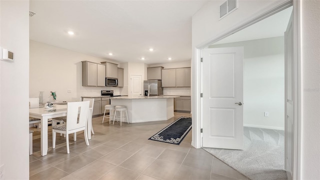 17817 Pastureland Ave, Lakewood Ranch, FL 34211 - kitchen with stainless steel appliances, gray cabinetry, a center island with sink, a kitchen breakfast bar, and recessed lighting