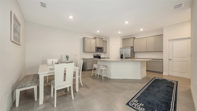 17817 Pastureland Ave, Lakewood Ranch, FL 34211 - kitchen with gray cabinets, appliances with stainless steel finishes, a center island with sink, light tile patterned flooring, and recessed lighting