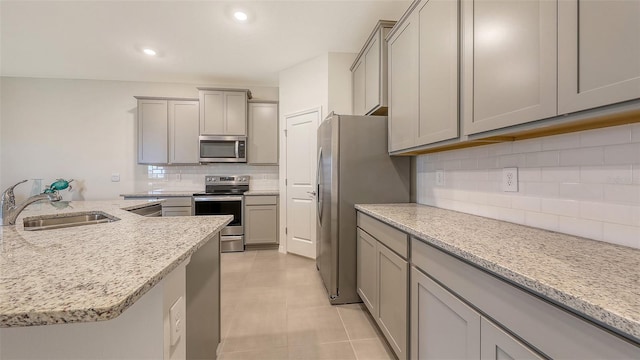 17817 Pastureland Ave, Lakewood Ranch, FL 34211 - kitchen featuring appliances with stainless steel finishes, gray cabinetry, tasteful backsplash, light tile patterned floors, and light stone counters