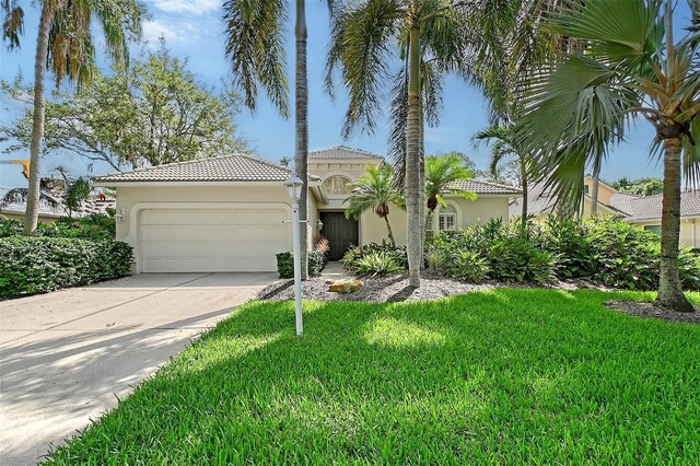 5839 Los Verdes Ct, Bradenton, FL 34210 - mediterranean / spanish house featuring stucco siding, a tiled roof, a garage, a front lawn, and concrete driveway