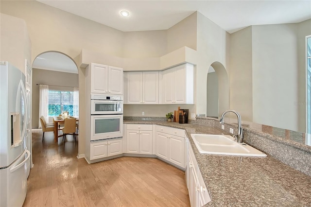 5839 Los Verdes Ct, Bradenton, FL 34210 - kitchen featuring stainless steel refrigerator with ice dispenser, double oven, arched walkways, white cabinetry, and light wood-style floors