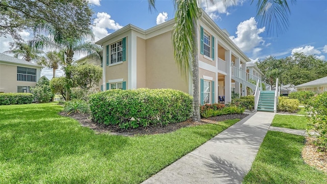 4211 Caddie Dr E Unit 202, Bradenton, FL 34203 - view of property exterior with stucco siding, a lawn, and stairs
