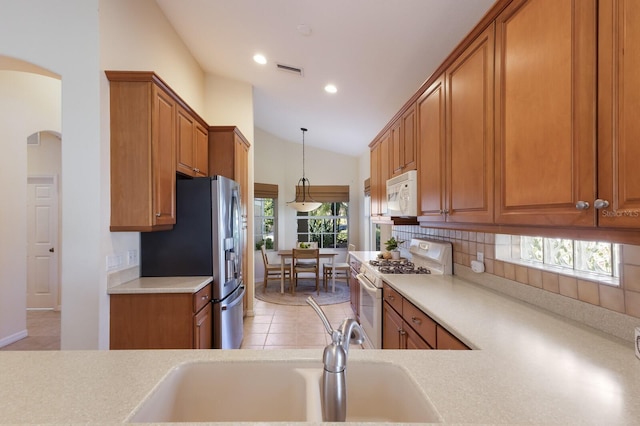 7419 Birds Eye Ter, Bradenton, FL 34203 - kitchen with white appliances, brown cabinetry, lofted ceiling, tasteful backsplash, and light countertops