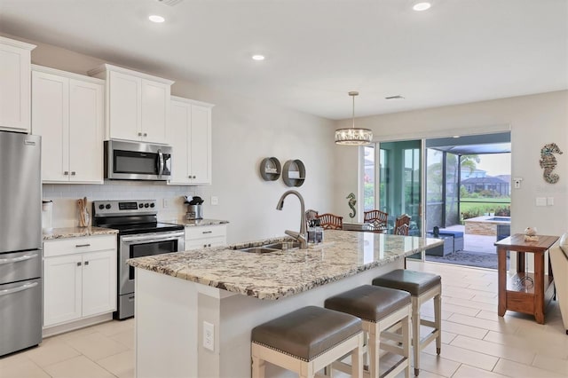 12564 Night View Dr, Sarasota, FL 34238 - kitchen with stainless steel appliances, decorative backsplash, a kitchen bar, light stone counters, and white cabinetry
