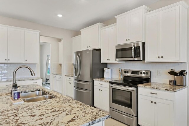 12564 Night View Dr, Sarasota, FL 34238 - kitchen with stainless steel appliances, white cabinetry, tasteful backsplash, light stone counters, and recessed lighting