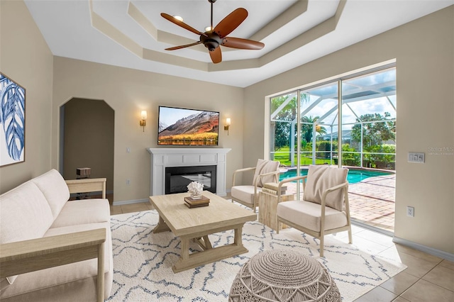 2148 Date Palm Way, Venice, FL 34292 - living room featuring ceiling fan, a raised ceiling, a sunroom, light tile patterned floors, and a glass covered fireplace
