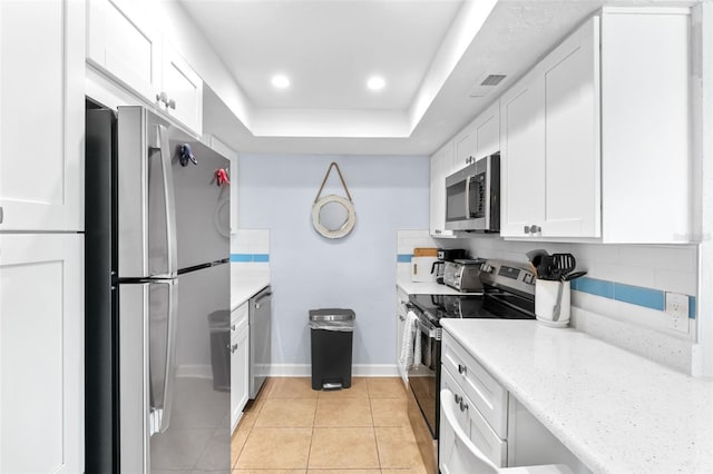 6312 Midnight Pass Rd Unit 102S, Sarasota, FL 34242 - kitchen featuring appliances with stainless steel finishes, a raised ceiling, white cabinetry, light tile patterned flooring, and tasteful backsplash