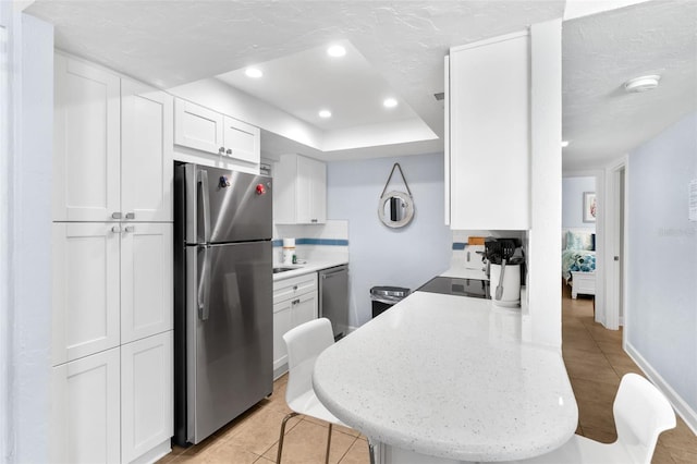 6312 Midnight Pass Rd Unit 102S, Sarasota, FL 34242 - kitchen with appliances with stainless steel finishes, white cabinetry, light tile patterned floors, a raised ceiling, and decorative backsplash