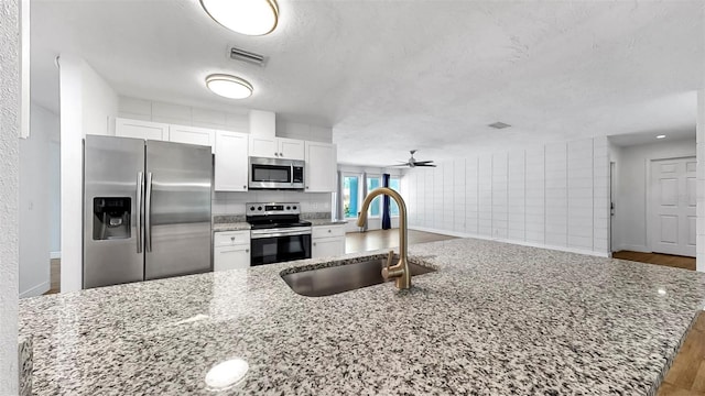 4455 Emerald Ridge Dr, Sarasota, FL 34233 - kitchen with stainless steel appliances, white cabinetry, ceiling fan, light stone countertops, and a textured ceiling